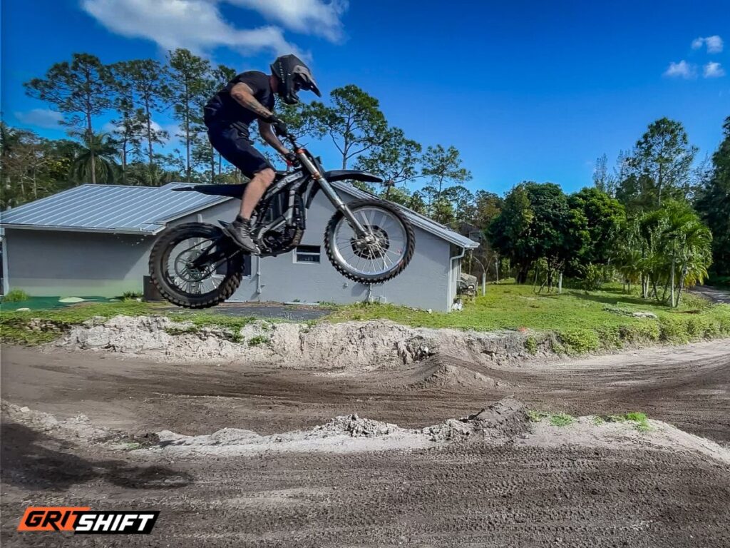 A rider on an electric dirt bike going over a big jump