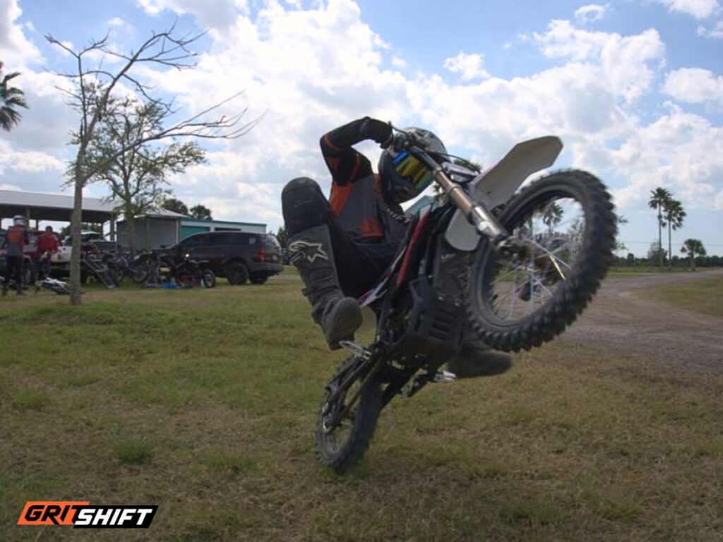 A rider doing a wheelie on an electric dirt bike