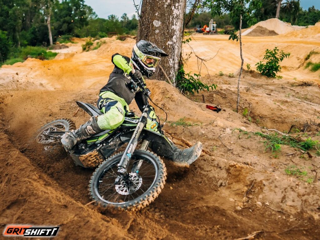 A rider riding an E Ride Pro on a motocross track with the swingarm 